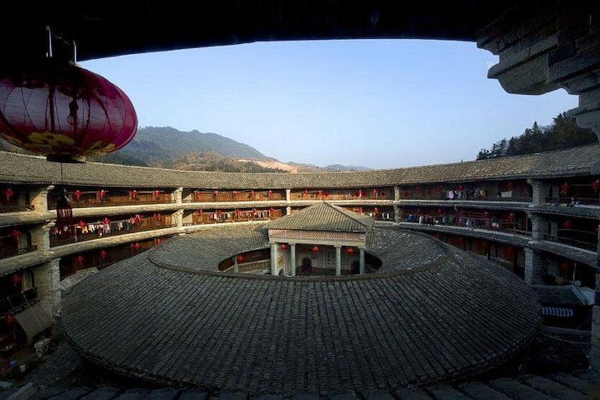 A traditional Chinese courtyard with a circular central area, multiple levels of buildings, and a mountainous backdrop. 2