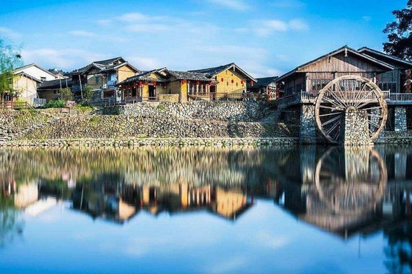 Traditional houses by a calm lake with a large water wheel. 1