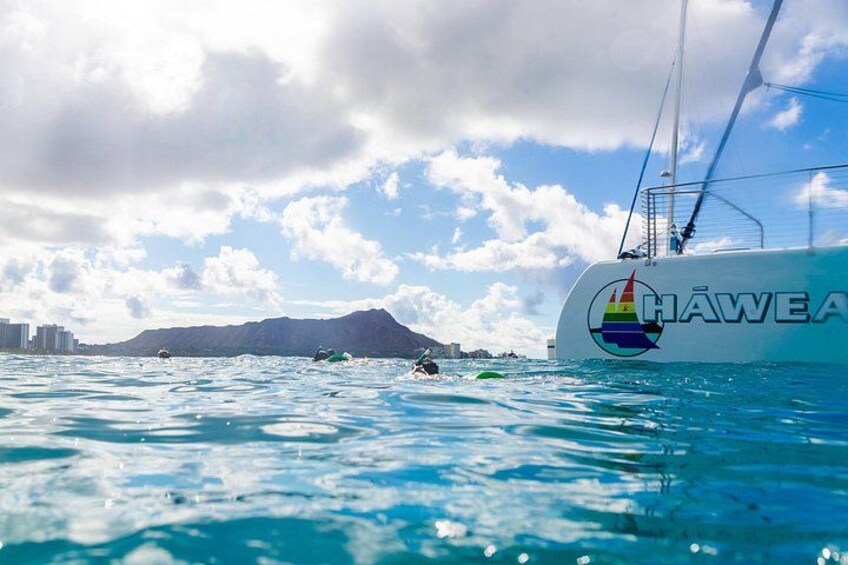 A cruise ship with a rainbow sail, water, and distant mountains. 2