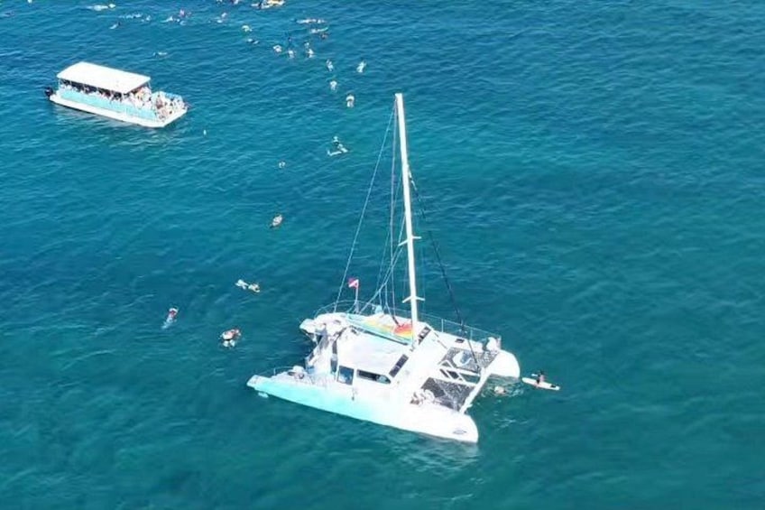 Un voilier doté d’un mât et de voiles, entouré d’une eau bleue et calme ainsi que d’autres bateaux. 2