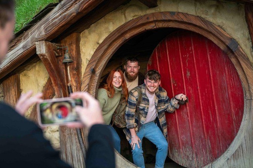 A wooden structure with a red door, a bell, and a person taking a photo. 2