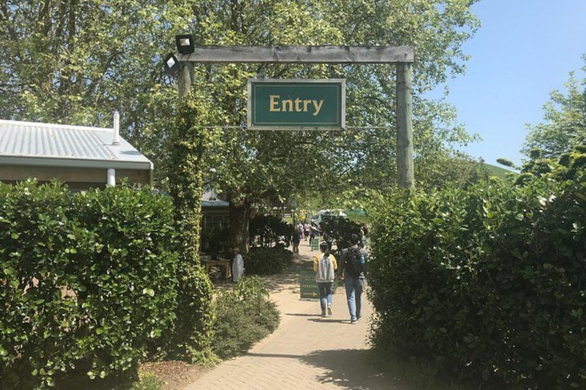 A pathway leading to an 'Entry' sign, surrounded by greenery and a building with a sloped roof. 5