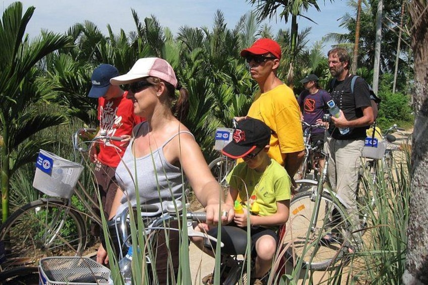 People riding bicycles through a field of tall plants, possibly a farm or botanical area. 2