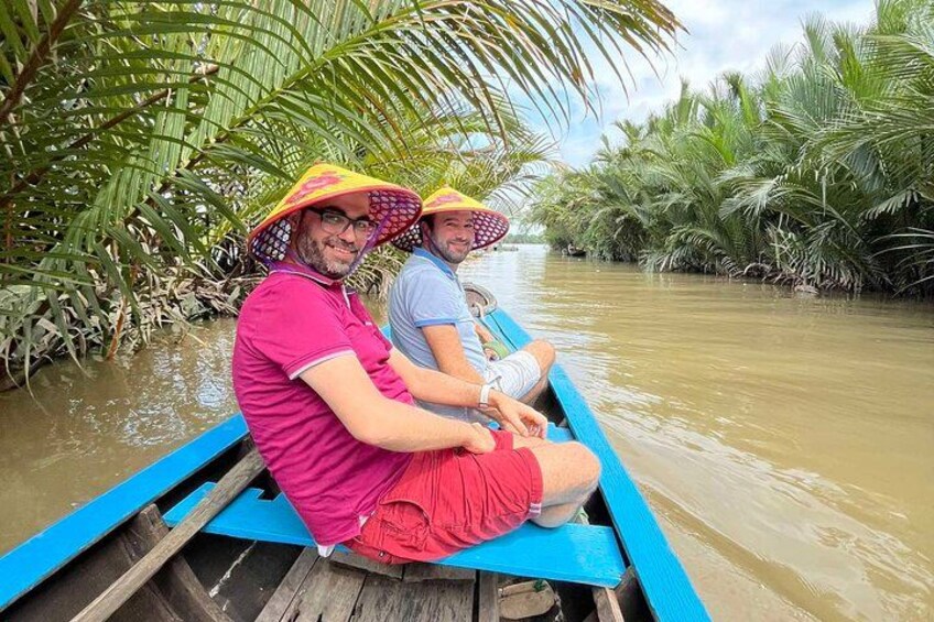 Dos personas en un bote sobre un río rodeado de palmeras. 2