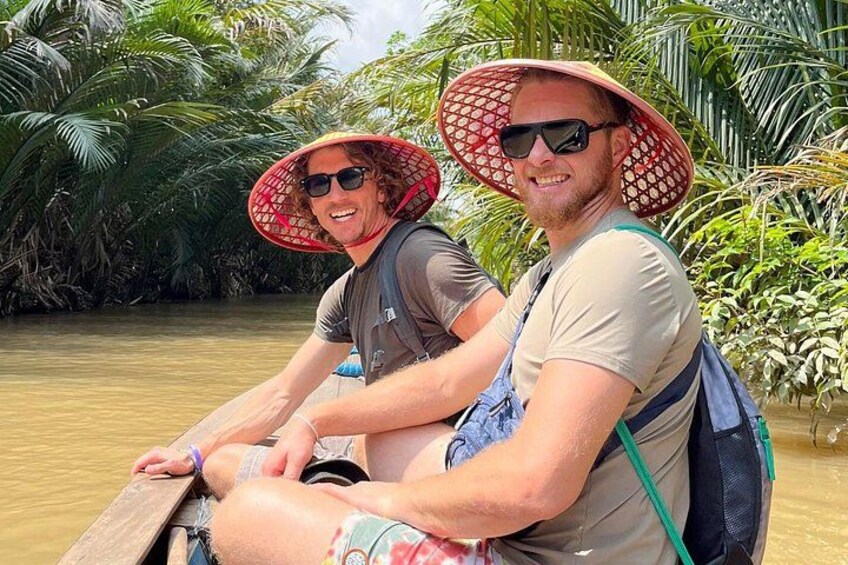 Two people in a boat on a river surrounded by tropical vegetation. 1
