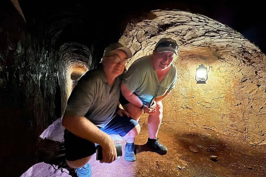 Two people sitting in a cave with a lantern on the wall. 3