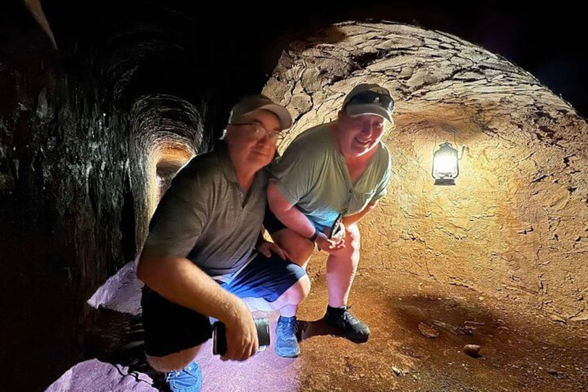 Due persone sedute all'interno di una grotta con una lanterna appesa al muro. 4