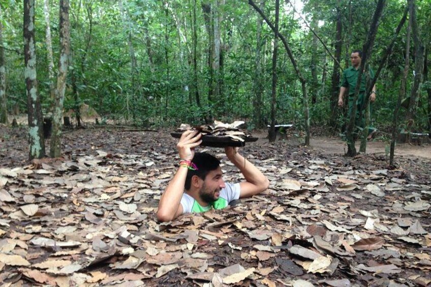 Una persona sdraiata sul terreno boschivo, circondata da foglie secche. 5