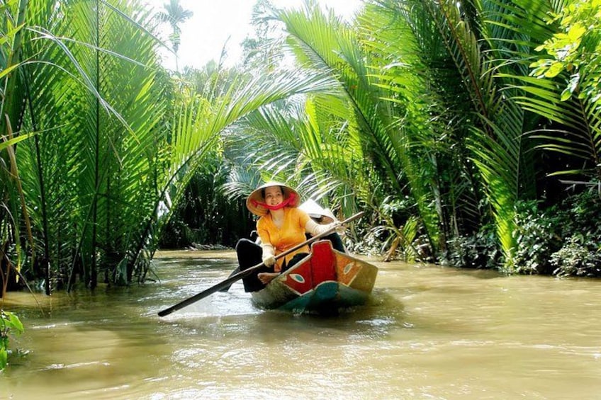 A person in a boat navigating through a river surrounded by dense tropical vegetation. 1