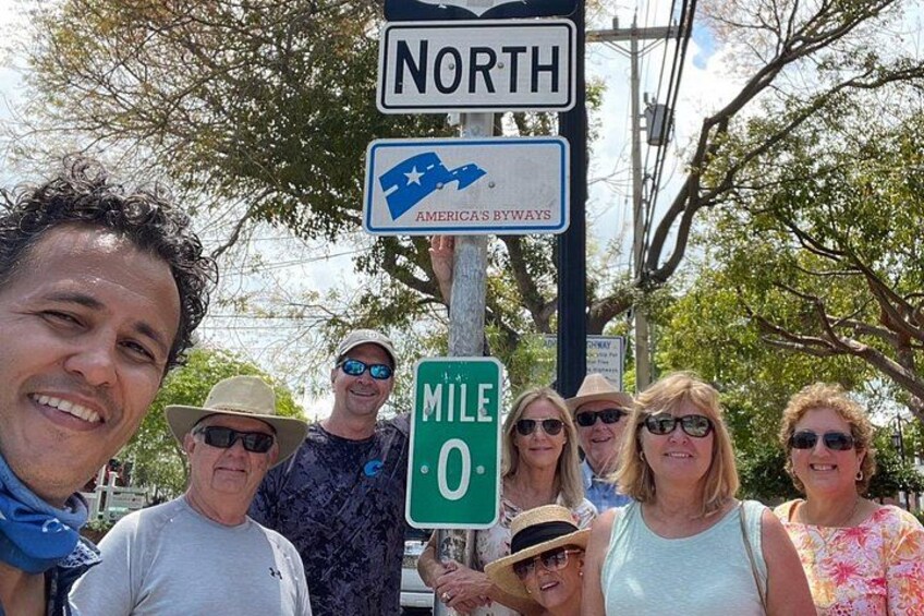 Un gruppo di persone in piedi di fronte a cartelli stradali che indicano 'NORD' e 'STRADE PANORAMICHE D'AMERICA'. 4