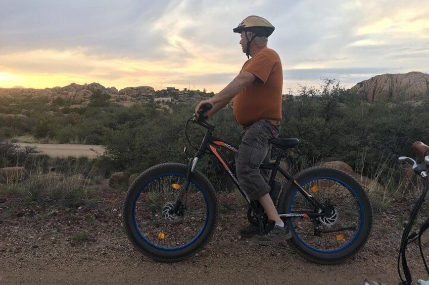 Una persona montando una bicicleta de montaña en un paisaje desértico con terreno rocoso y vegetación escasa. 1