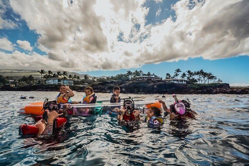 A group of people in a boat on a body of water with a cloudy sky and a distant shoreline with palm trees. 4