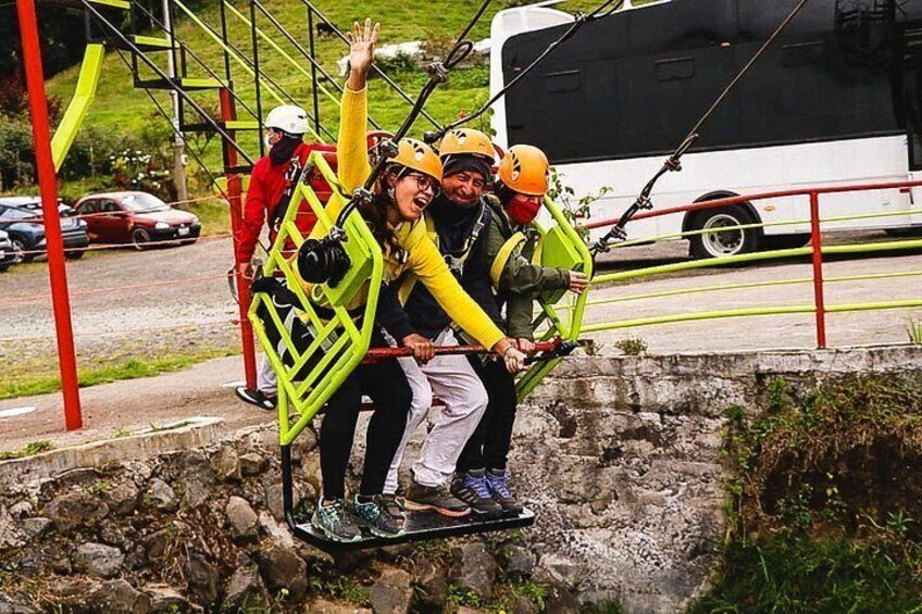 Persone su una zipline, un autobus bianco e un terreno roccioso. 5