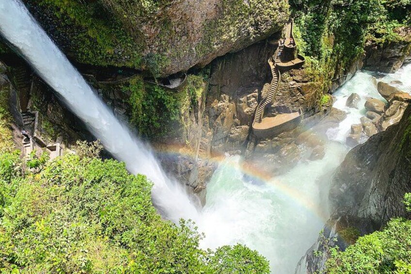 A waterfall cascading over rocks, a rainbow, and a viewing platform. 1