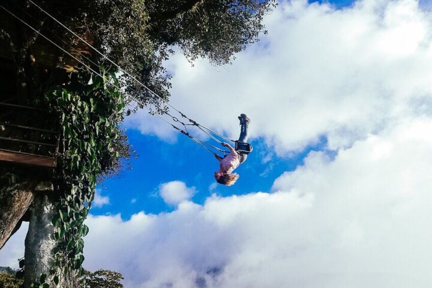A person bungee jumping with a harness, surrounded by trees and a blue sky with clouds. 2