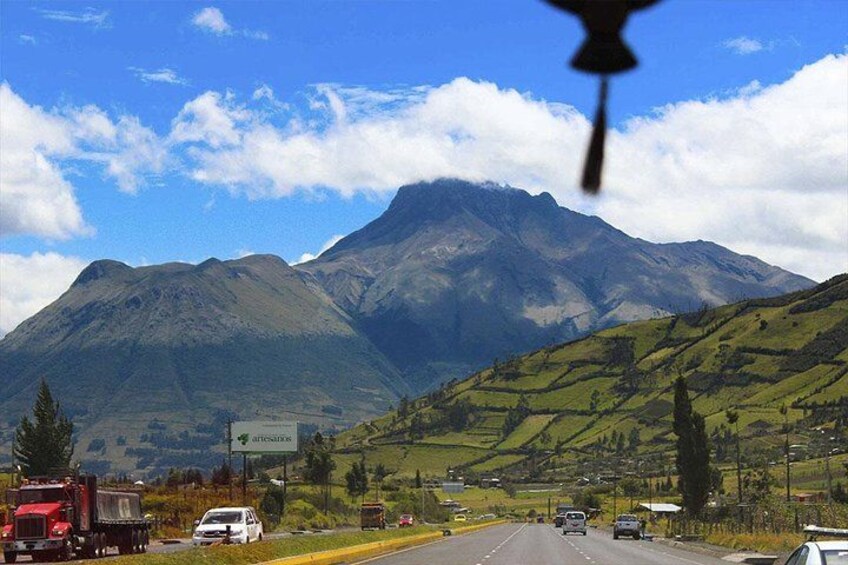 A road with vehicles, a mountain range, and a clear sky. 3