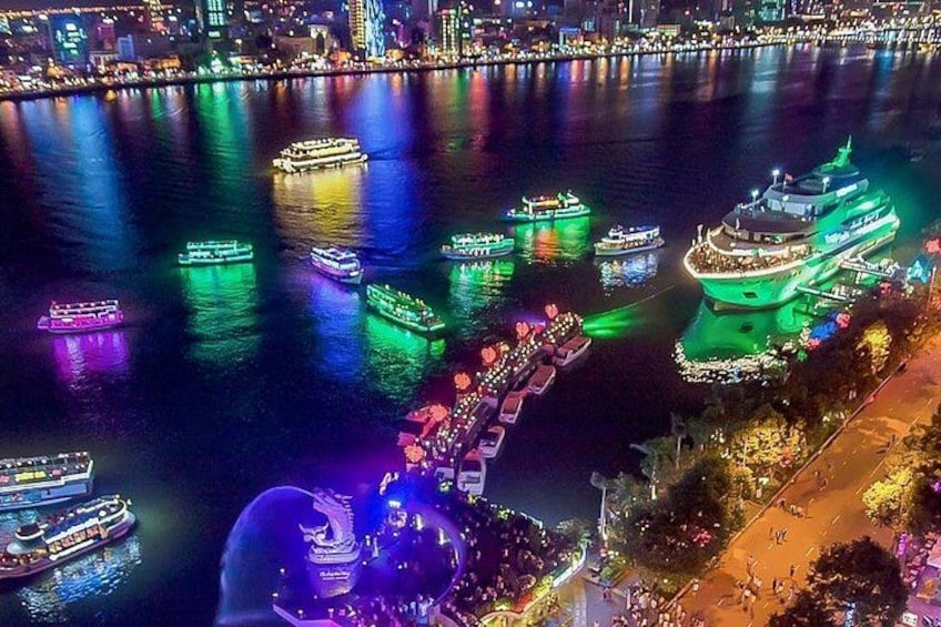 A nighttime river scene with illuminated boats and a large cruise ship docked at a pier. 1