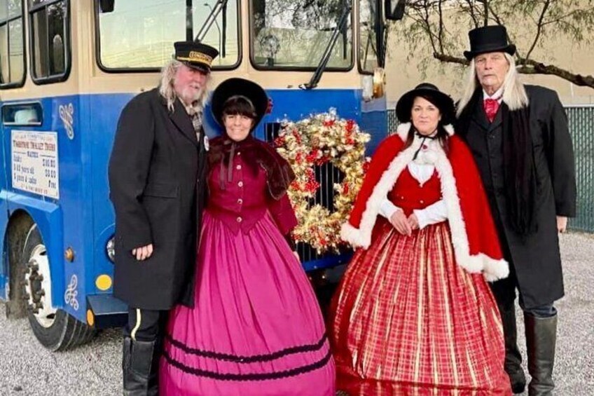 Quatre personnes, vêtues de costumes d’époque, se tiennent devant un autobus. 5