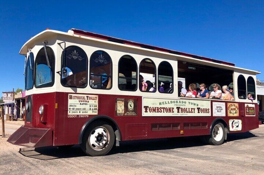 A historical trolley with 'Tombstone Trolley Tours' written on the side, parked on a clear day. 3