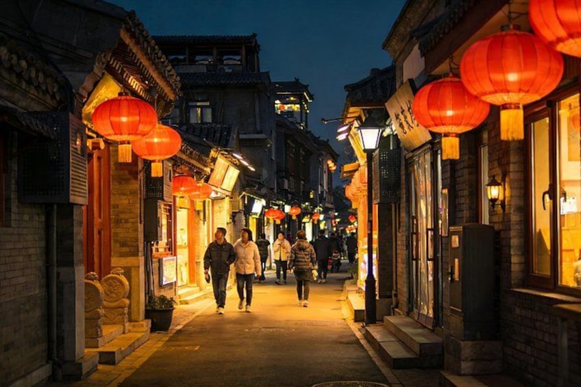 A narrow street with traditional buildings, illuminated by red lanterns and street lamps. 5
