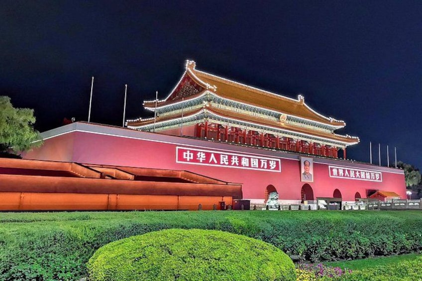 A traditional Chinese building with illuminated signage and a well-manicured garden. 1