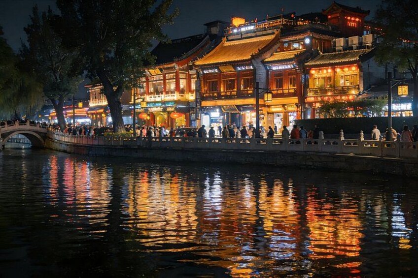 A traditional Chinese building with illuminated windows and a reflection on the water. 3