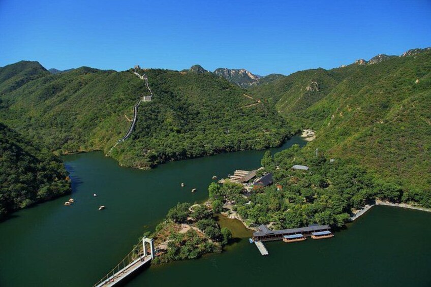 A river winding through a mountainous landscape with a bridge, boats, and buildings. 4