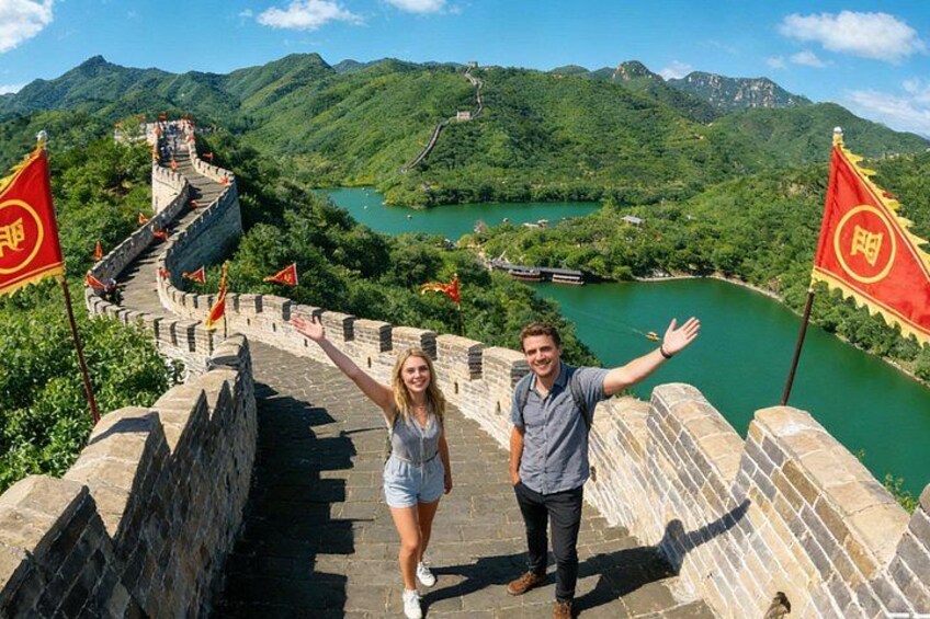 A person standing on the Great Wall of China with a river and mountains in the background. 1