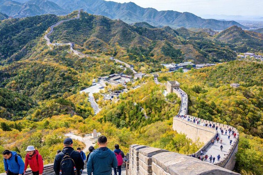 The Great Wall of China winding through a mountainous landscape with tourists walking along the path. 2