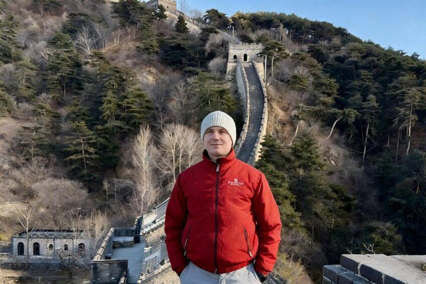 A person standing on a stone platform with a mountainous landscape and a long, winding road in the background. 1