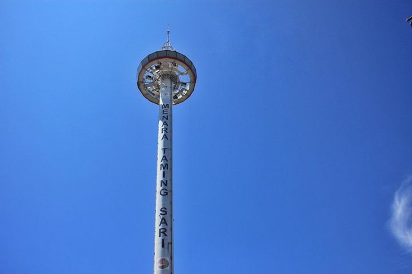 Ett högt torn med inskriptionen ”MENARA TAMIYA SARI” mot en klarblå himmel. 5