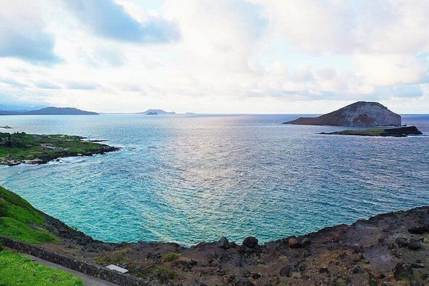 Un paisaje costero con costa rocosa, mar tranquilo y islas a lo lejos. 2