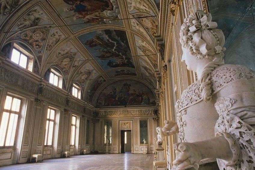 Un interior ornamentado con una estatua imponente, techos abovedados y frescos clásicos. 2