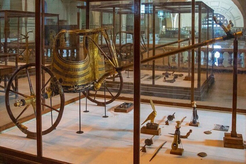 En museumsudstilling med en gylden triumfvogn og forskellige oldgamle artefakter. 5