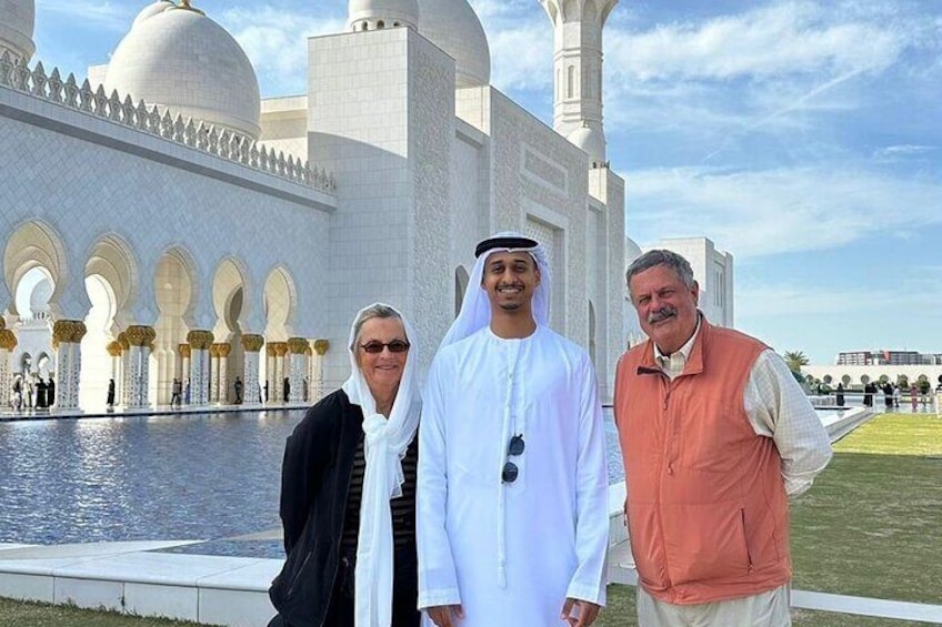 A group of people standing in front of a large white building with domes and arches. 4