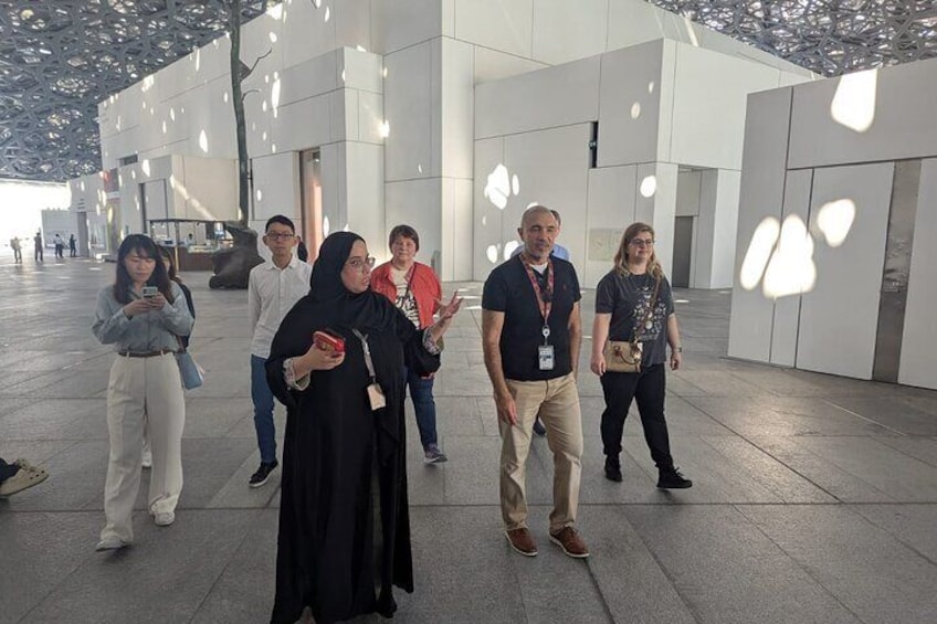 A group of people walking in a modern architectural space with geometric patterns on the ceiling. 3