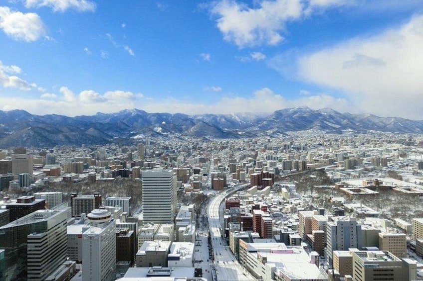 A cityscape with snow-covered buildings and mountains in the background. 3