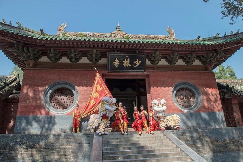 A traditional Chinese building with a tiled roof, a signboard, and a group of people in red attire. 3