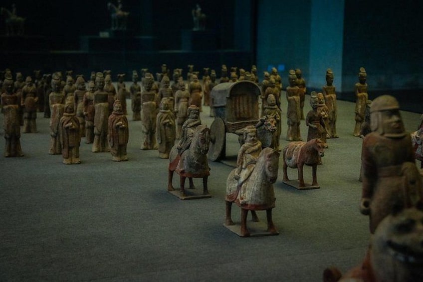 A collection of terracotta soldiers arranged in rows, some mounted on horses, in a museum setting. 2
