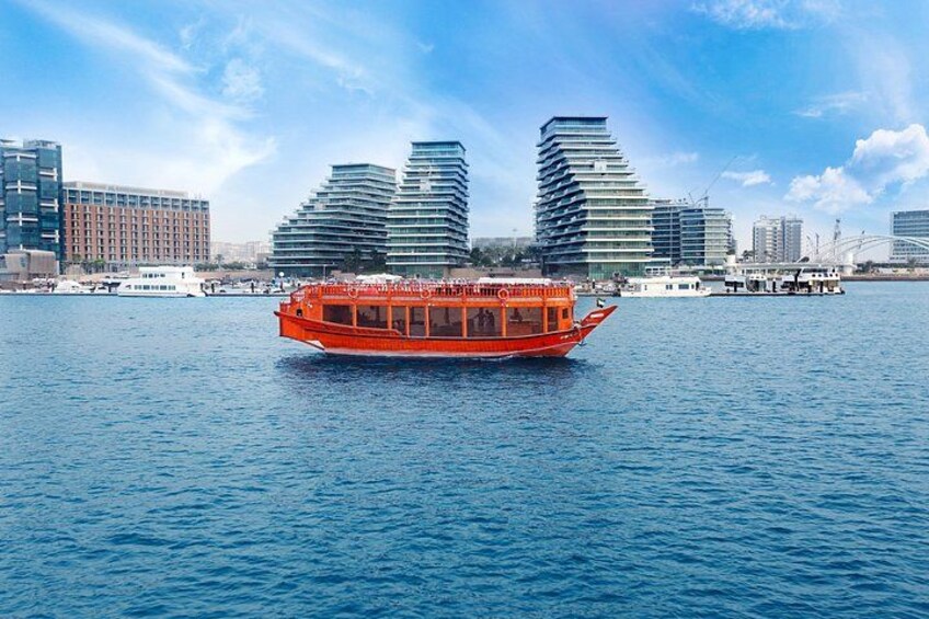 A red boat on a body of water with modern buildings in the background. 5