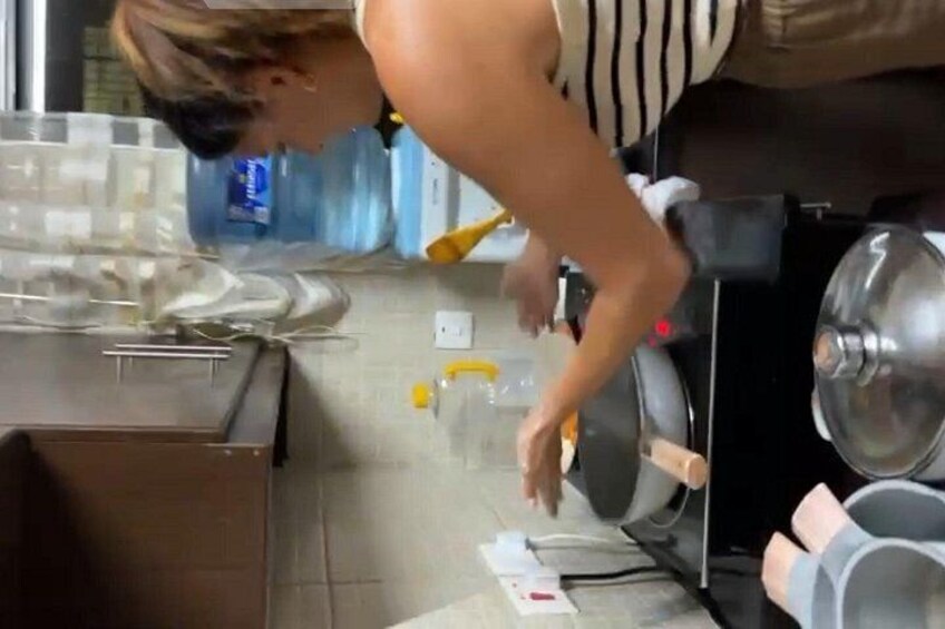 A person working at a kitchen counter with a sink, a stove, and various kitchen items. 5