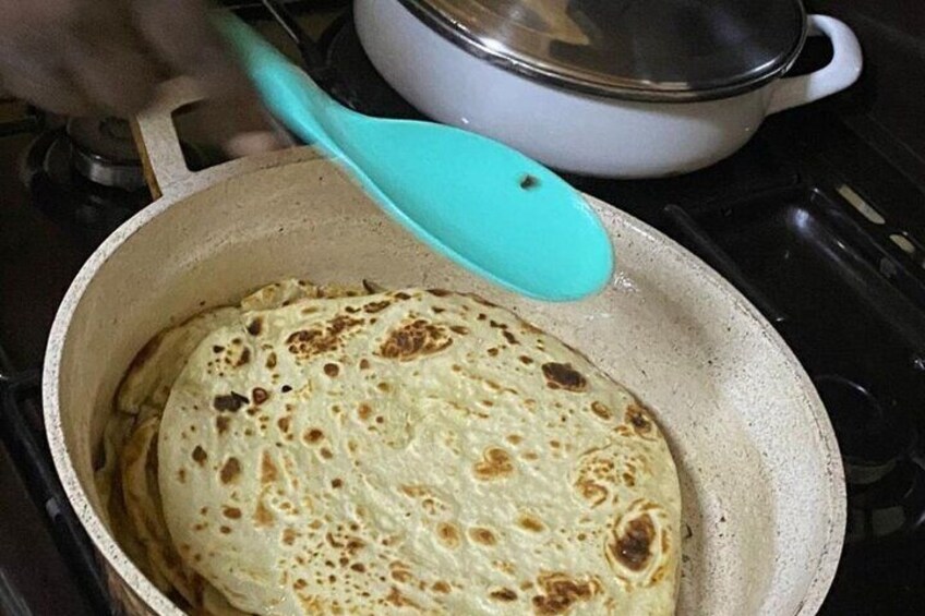A flatbread cooking in a pan on a stove. 1