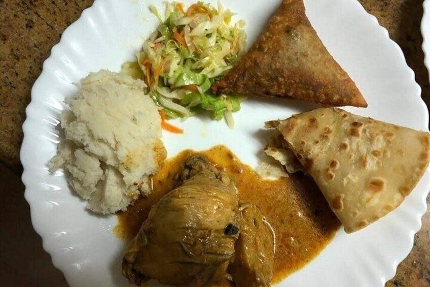 A plate with a piece of meat, a side of mashed potatoes, a coleslaw, and two triangular pieces of flatbread. 4