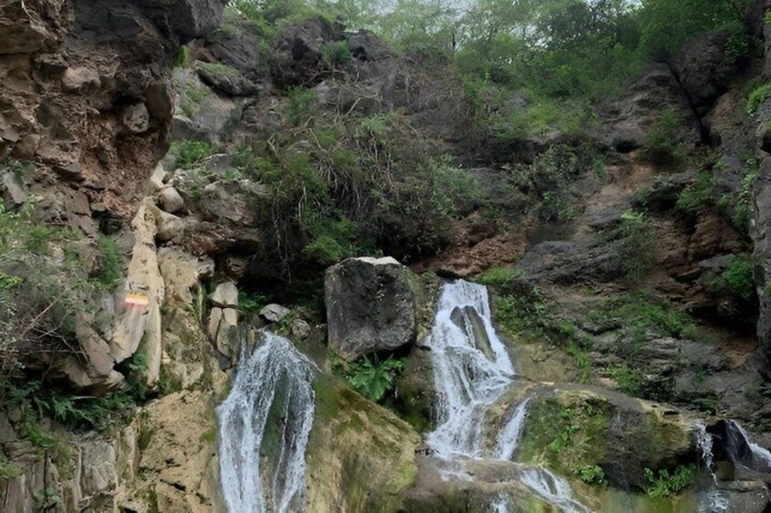 A waterfall cascading over rocks in a forested area. 2