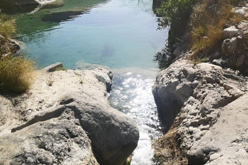 A clear water body surrounded by rocky terrain. 4