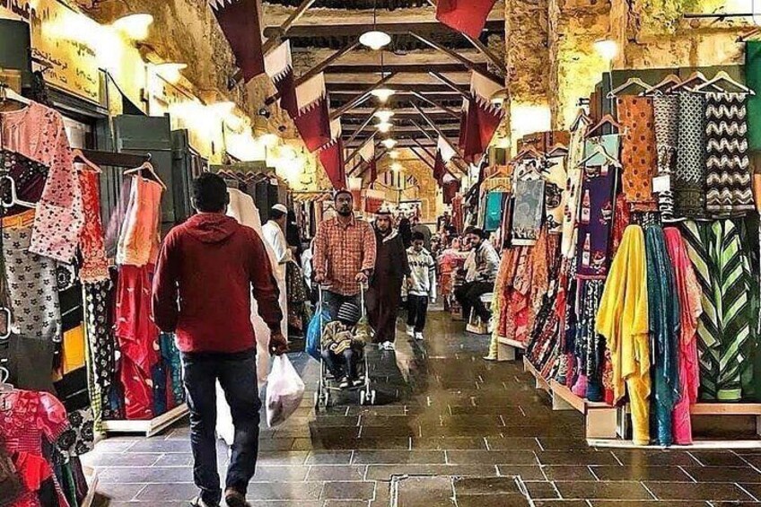 Un mercado cubierto animado con diversos puestos que ofrecen textiles y ropa. 1
