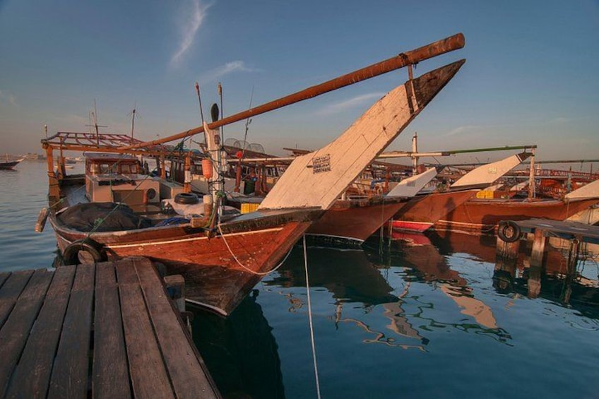 Un muelle de madera con un bote, agua tranquila y otros barcos al fondo. 2