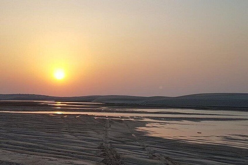 Un coucher de soleil sur un paysage plat, avec une étendue d'eau calme qui reflète le ciel. 2