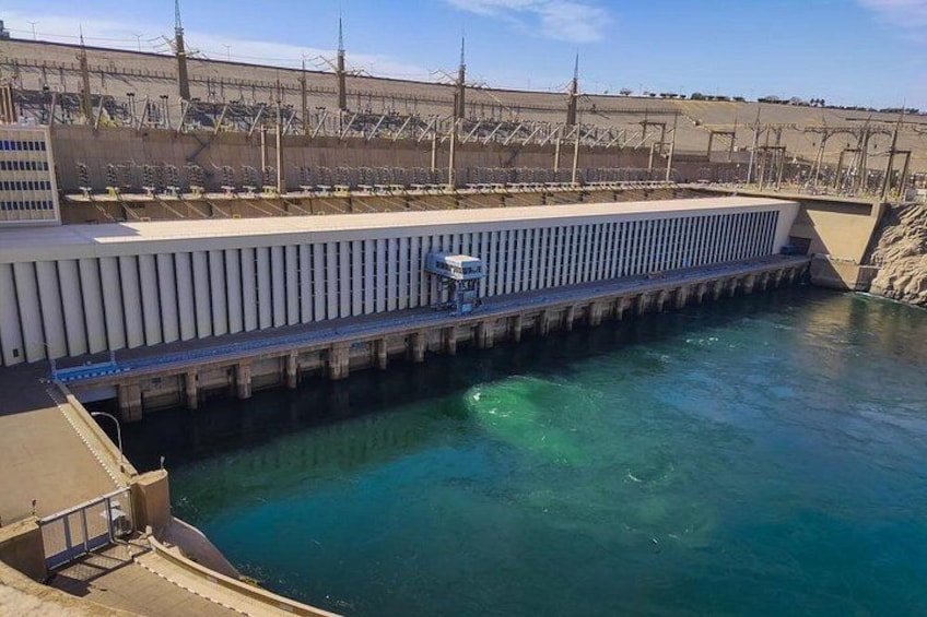 Een dam met stromend water, een controlegebouw en een groot stuwmeer op de achtergrond. 3