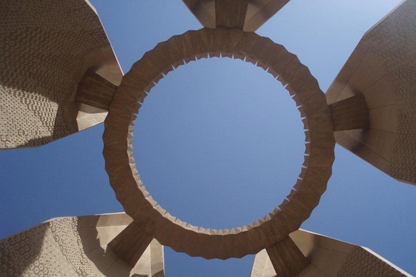 Een rond architectonisch bouwwerk met een opening in het midden, tegen een helderblauwe lucht. 4